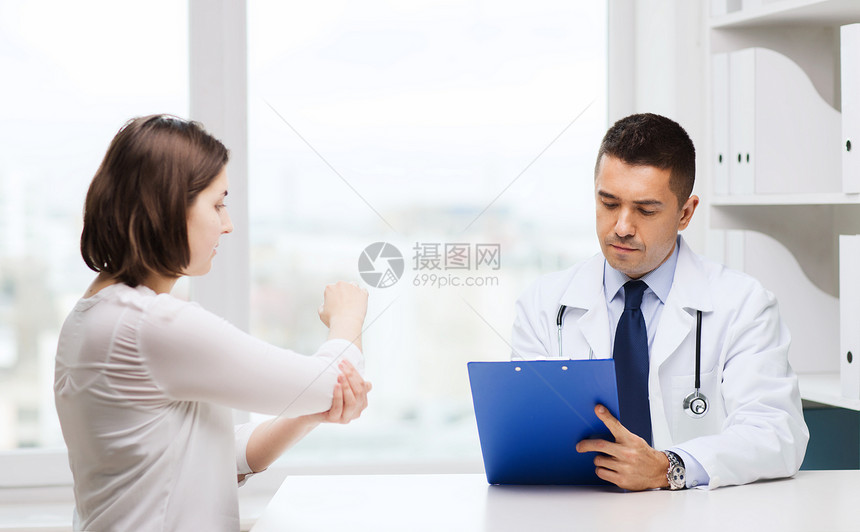 医学,保健人的轻的妇女向医生展示肘部与剪贴板会议医院图片