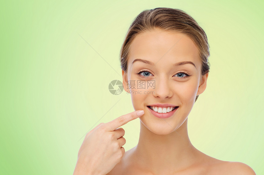 美丽,人,牙科护理卫生快乐的轻女人指着她的微笑牙齿绿色的背景图片