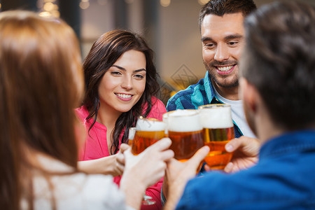 休闲,饮料,庆祝,人假日的微笑的朋友餐馆酒吧喝啤酒碰杯图片