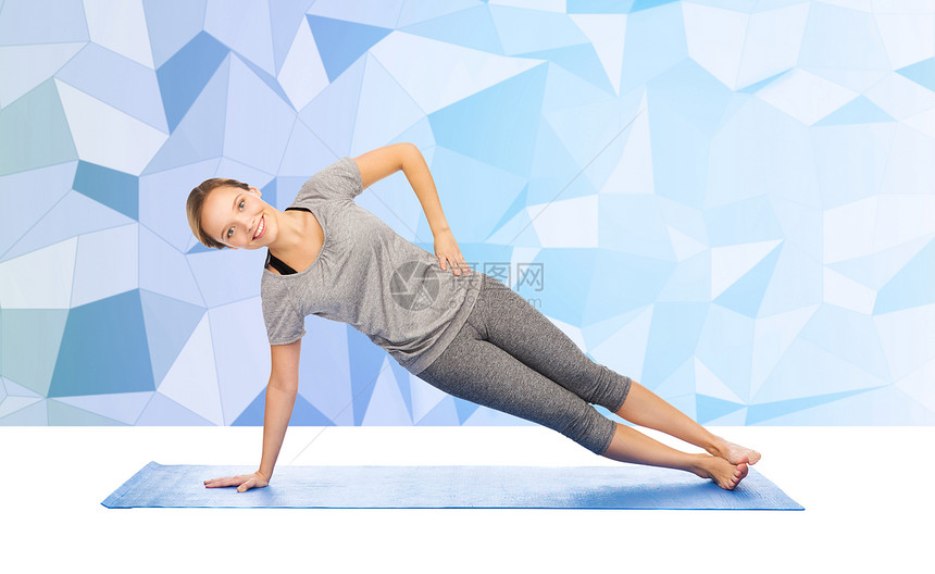健身,运动,人健康的生活方式妇女瑜伽侧板姿势垫子上的低聚背景图片