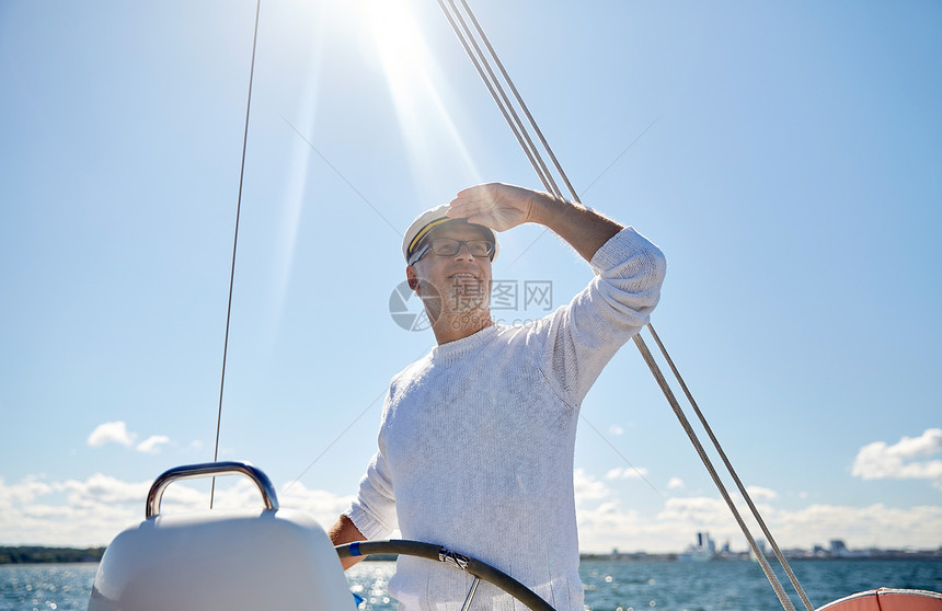 快乐的老人戴着船长帽子看着遥远的海上图片