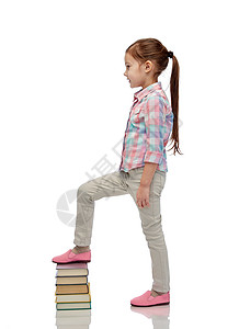 童,学校,教育人的快乐的小女孩踩书堆上图片