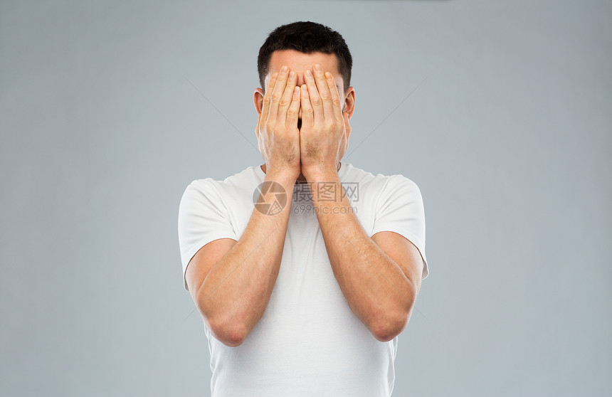 人,危机,情绪压力的男人穿着白色T恤,双手覆盖灰色背景上图片