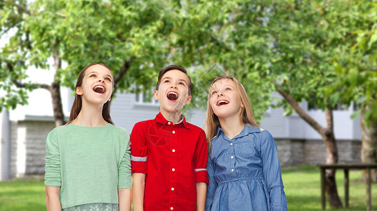 童,时尚,友谊人的快乐惊讶的男孩女孩张开嘴巴仰望私人住宅后院的背景图片