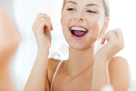 保健,牙科卫生,人美容微笑的轻妇女用牙线清洁牙齿,并家里的浴室看镜子图片