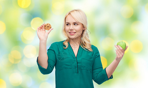 健康饮食,垃圾食品,饮食选择人的微笑的女人选择苹果饼干的绿灯背景图片
