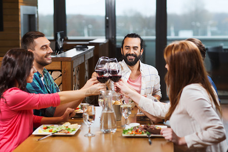 休闲,庆祝,食物饮料,人假日的微笑的朋友餐厅吃晚餐喝红酒图片