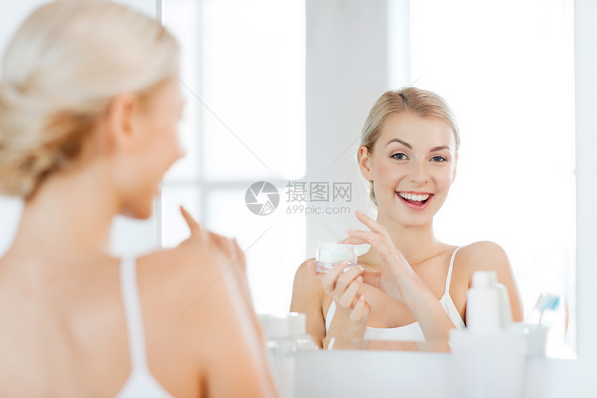 美丽,皮肤护理人的微笑的轻妇女应用奶油镜子家里的浴室图片