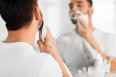美容,剃须,美容人的男人脸上除剃须泡沫与毛巾镜子家里的浴室图片