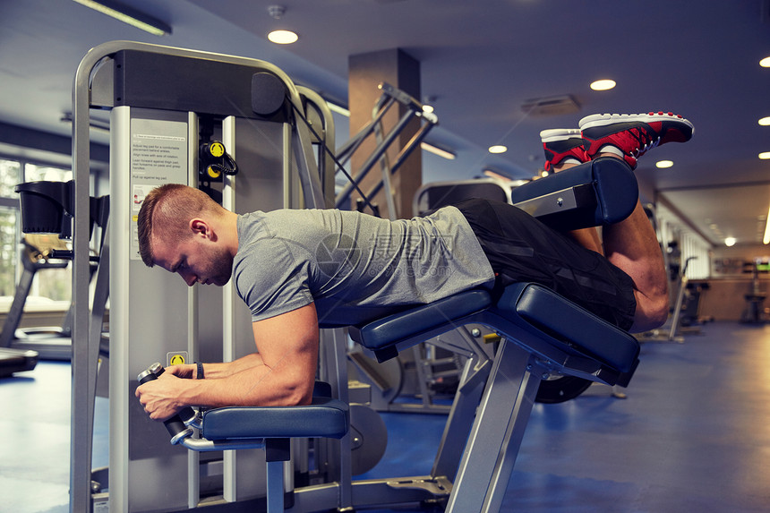 运动,健身,健美,生活方式人的男人锻炼弯曲肌肉腿部卷曲机健身房图片