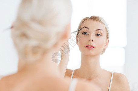 美容,化妆,化妆品,早晨人的轻的女人用刷子画眉,家里的浴室照镜子图片