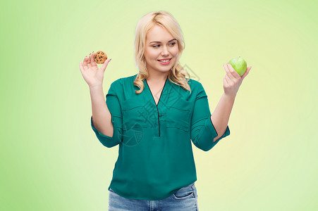 健康饮食,垃圾食品,饮食选择人的微笑的女人选择苹果饼干的绿色自然背景图片