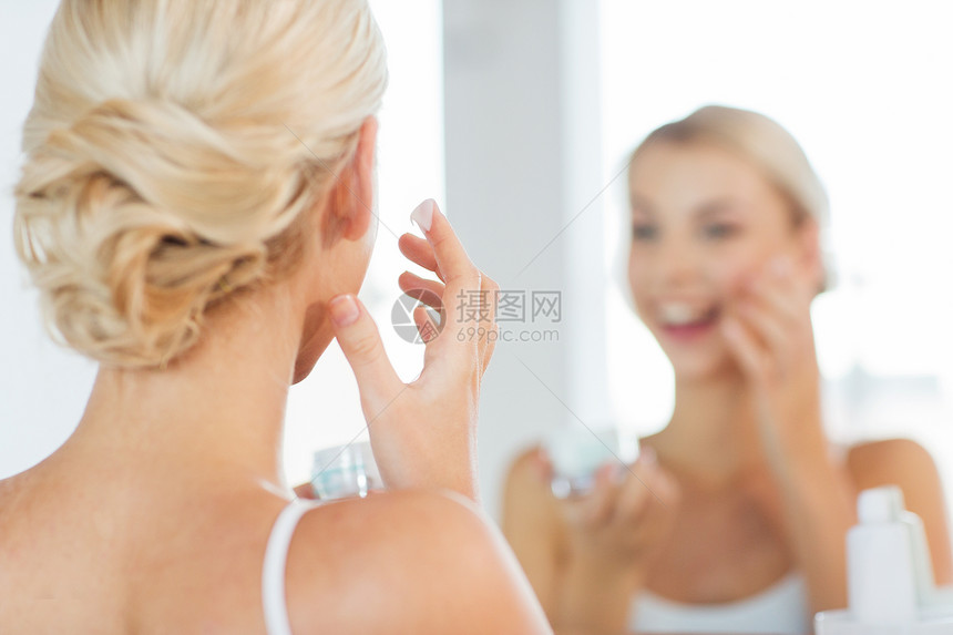 美丽,皮肤护理人的近距离微笑的轻妇女应用奶油镜子家庭浴室图片