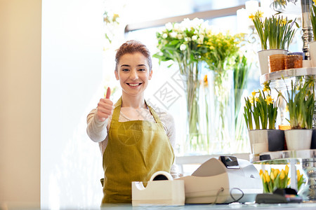 人,商业,销售花艺的快乐微笑的花店妇女花店的现金箱竖大拇指图片