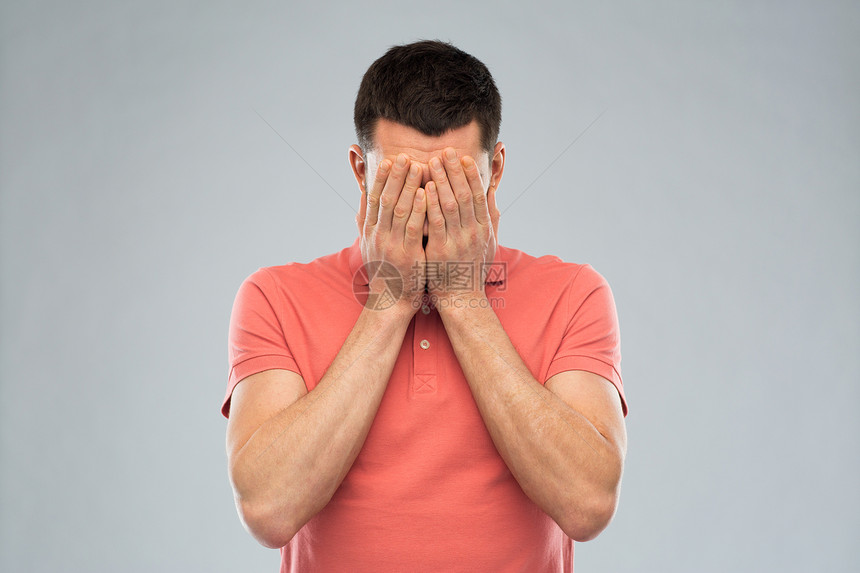 人,危机,情绪压力的男人T恤上用手遮住他的脸灰色的背景图片