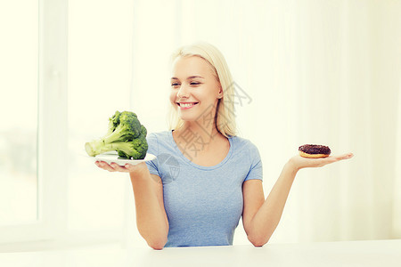 健康饮食,垃圾食品,饮食选择的人的微笑的女人选择西兰花甜甜圈家里图片