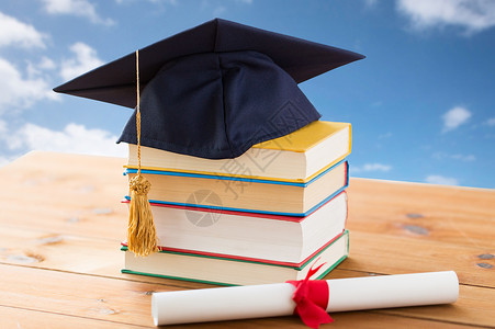 教育学校毕业知识蓝天云背景的木桌上贴上带文凭的书籍黑板图片