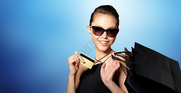 销售,财务,时尚,人奢侈的快乐美丽的轻女人戴着黑色太阳镜,带着信用卡购物袋,蓝色背景珠宝高清图片素材