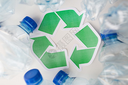 废物回收再利用垃圾处理环境生态桌子上贴上绿色回收符号的废旧塑料瓶背景图片