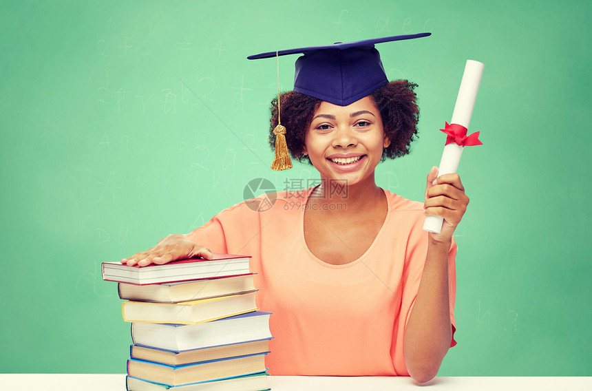 教育,学校,知识,毕业人的快乐的微笑非裔美国学生女孩学士帽与书籍文凭的绿色粉笔板背景图片