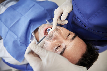 人医学口腔医学保健理念牙科诊所办公室用牙科镜检查男患者的牙齿图片