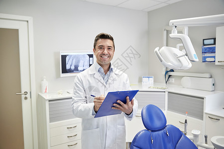 人,医学,口腔医学医疗保健快乐的中男牙医穿着白色外套,牙科诊所办公室写字板图片