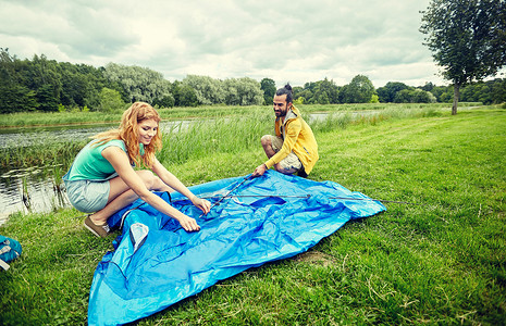 野营,旅游,徒步旅行人们的快乐的夫妇户外搭帐篷图片