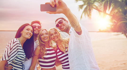 暑假,旅游,技术人的群微笑的朋友与智能手机拍照自拍异国情调的热带海滩背景图片