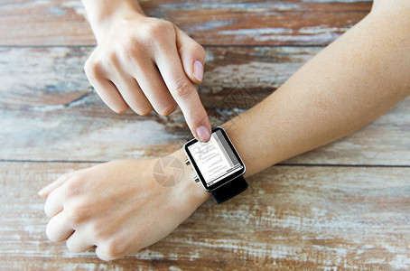 智能腕表商业,现代技术,编程人的女的手智能手表与编码屏幕上的木制桌子背景