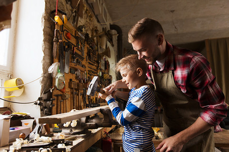 幸福的家庭,木工,木工人的父亲小儿子用锤击钉木板车间图片