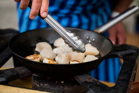 烹饪,亚洲厨房,销售海洋食品亚洲街头市场上,用钳子煎扇贝来烹饪图片
