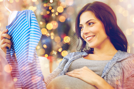 假期,怀孕,人孩子的服装快乐的女人抱着看蓝色的男婴紧身衣诞灯背景图片