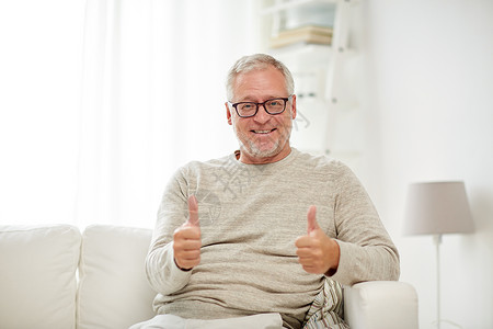 老人,手势人的微笑的老人戴着眼镜,坐沙发上,家里竖大拇指图片