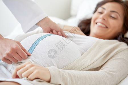 怀孕,医学,保健人们的密切产科医生与厘米磁带测量孕妇肚子医院背景图片