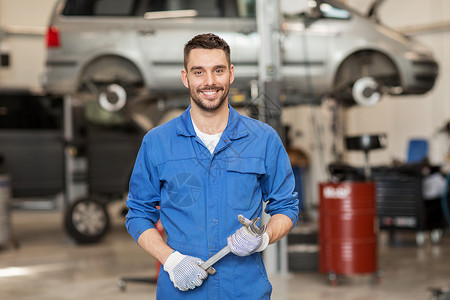 修理车库汽车服务,维修,维护人的汽车技工史密斯与扳手车间背景