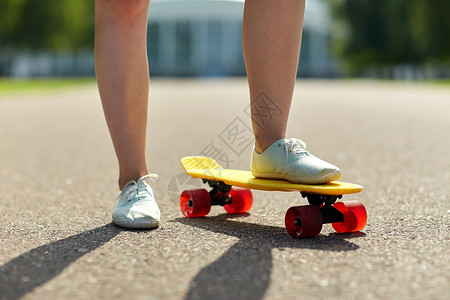 时髦的巡洋舰滑板,休闲,极限运动人的近十几岁的女孩腿骑短现代巡洋舰滑板路上背景