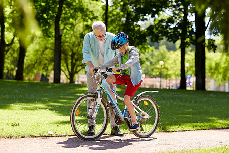 家庭,世代,安全人的快乐祖父教男孩如何骑自行车夏季公园图片