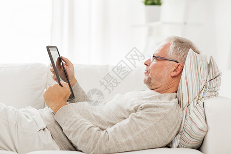 技术,人生活方式,远程学老人与平板电脑电脑躺沙发上家图片
