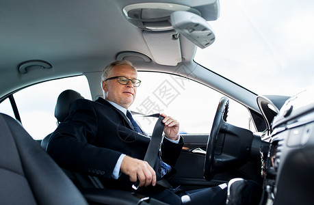运输,商务旅行,安全人的高级商人开车前系好安全带图片