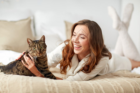 笑着的猫宠物,舒适,休息人的快乐的轻女人猫躺床上家背景