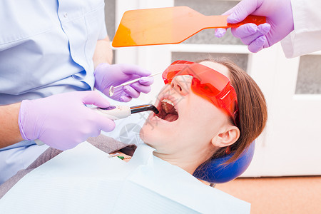 病人躺特殊的眼镜,以防止激光,而牙医工作与牙科治疗光牙科聚合图片
