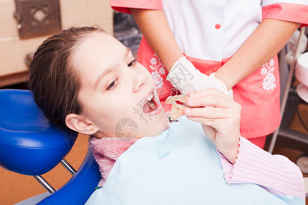 个女孩试图为牙齿牙套建立个固定器,坐牙科椅子上图片
