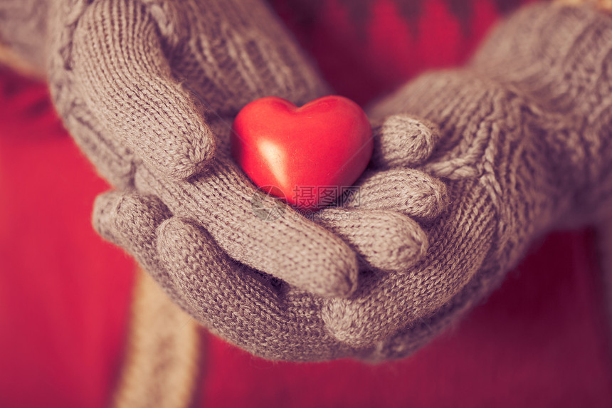 手的特写,灰色的针手套,抱着红色的心情人节的图片