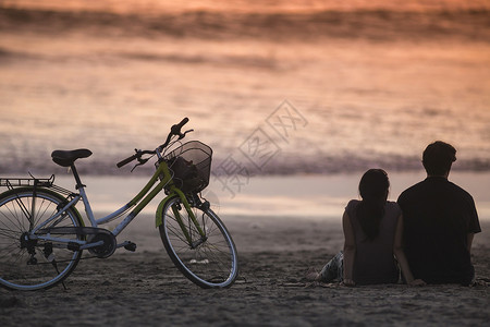 印度尼西亚巴厘岛日落时海滩上可爱的夫妇的剪影图片