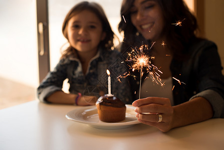 母亲女儿用纸杯蛋糕火花庆祝生日图片