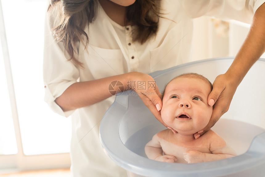 可爱的新生婴儿由母亲洗澡图片