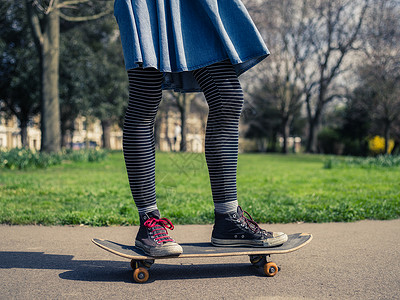 个穿着时髦衣服的轻女人正公园里玩滑板背景图片