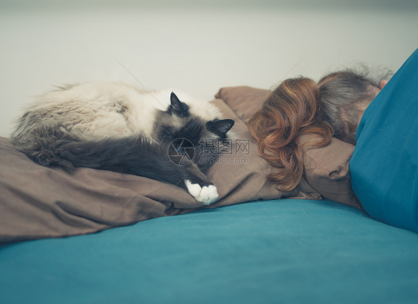 个轻的女人睡张床上,旁边只猫图片