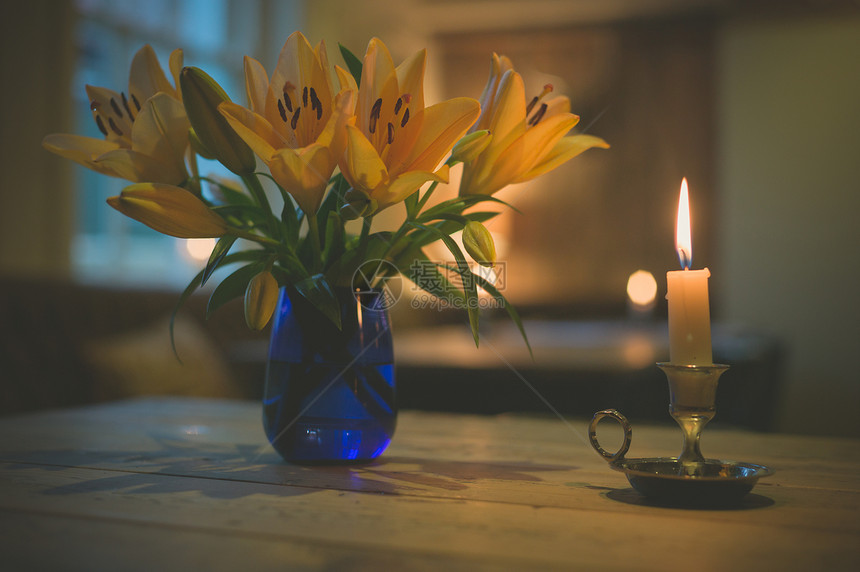 支点燃的蜡烛个花瓶,餐厅的桌子上放着盛开的百合花图片
