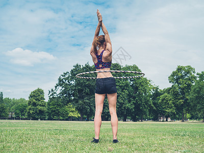 个健康运动的轻女人正公园里锻炼个呼啦圈,个阳光明媚的夏天图片